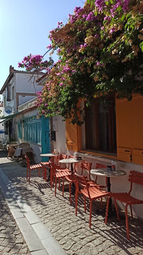 Free A picturesque street cafe with colorful chairs and bougainvillea on a sunny day. Stock Photo