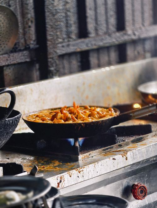 Free A simmering pan of pasta sauce on a gas stove in a rustic kitchen setting. Stock Photo