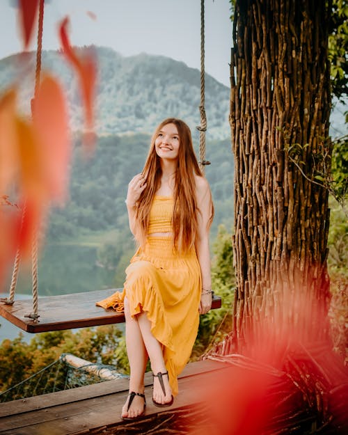 Free Woman In Yellow Clothing Sitting On Brown Wooden Swing Stock Photo