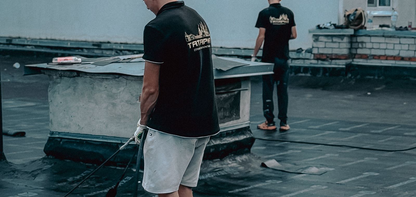 Roofers installing membrane on a flat roof