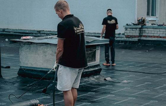 Roofers installing membrane on a flat roof