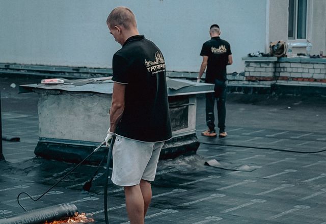 Roofers installing membrane on a flat roof