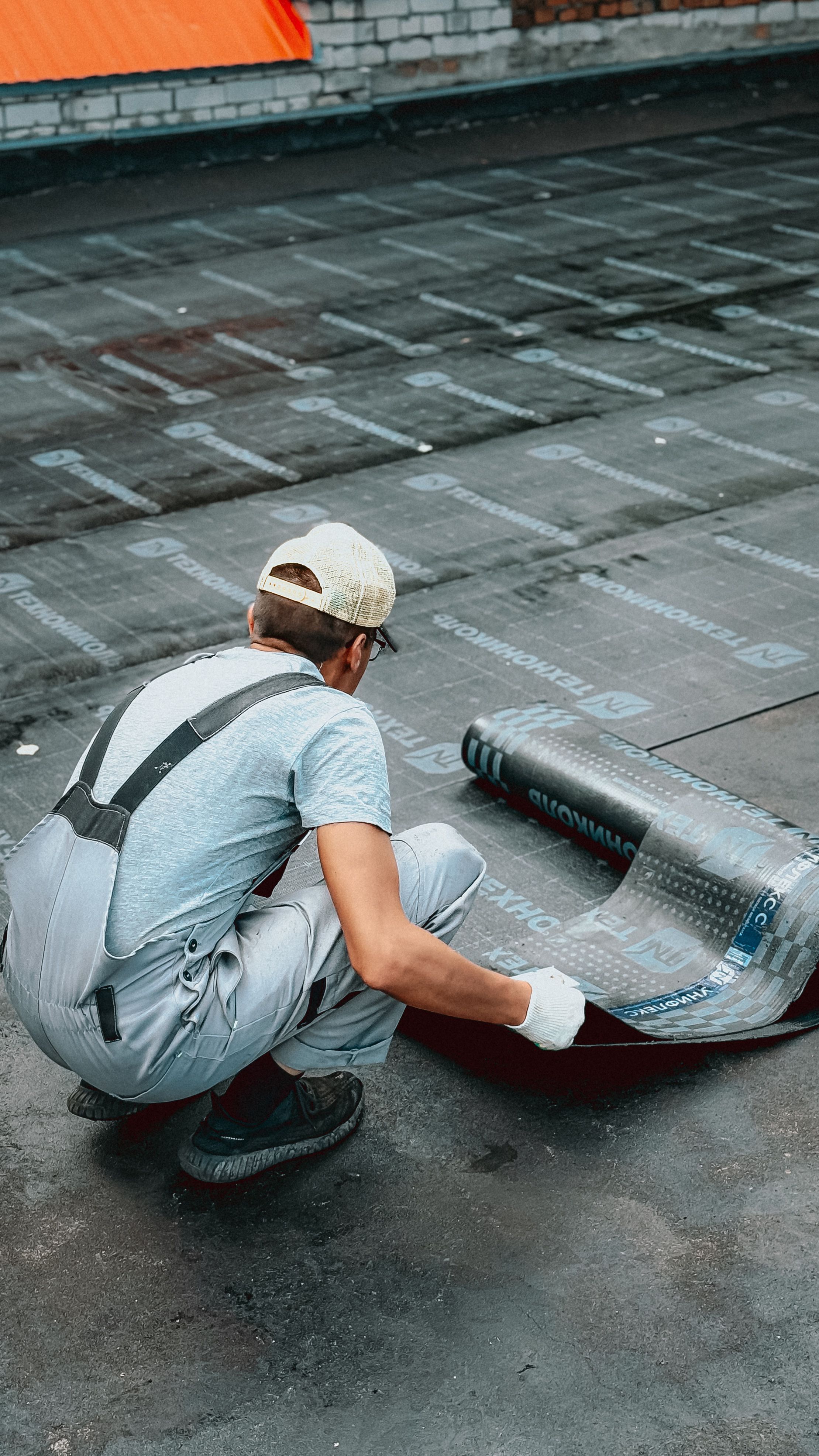 Operaio inginocchiato al lavoro su una copertura piana