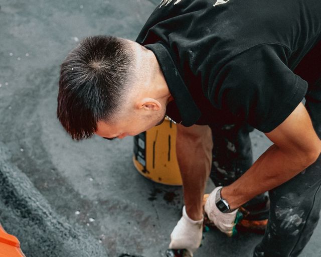 Reflective roof surface being applied Worker using a roller to apply a reflective layer on a roof