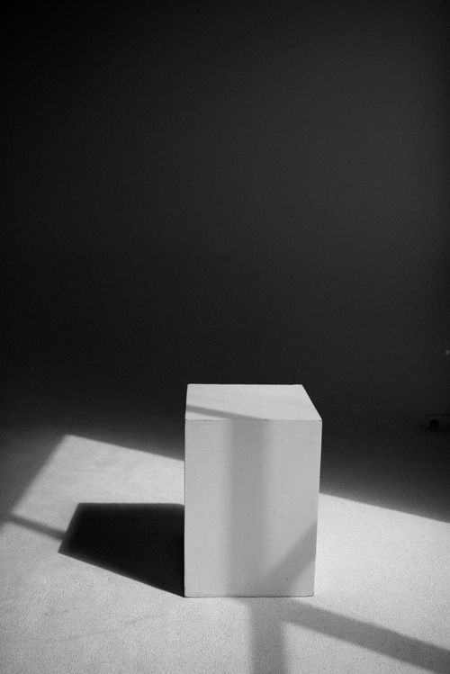 Free A minimalist black and white photo featuring a cube with dramatic lighting and shadows. Stock Photo