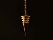 一个金色钟摆优雅地悬在神秘的黑色背景上，链条垂落