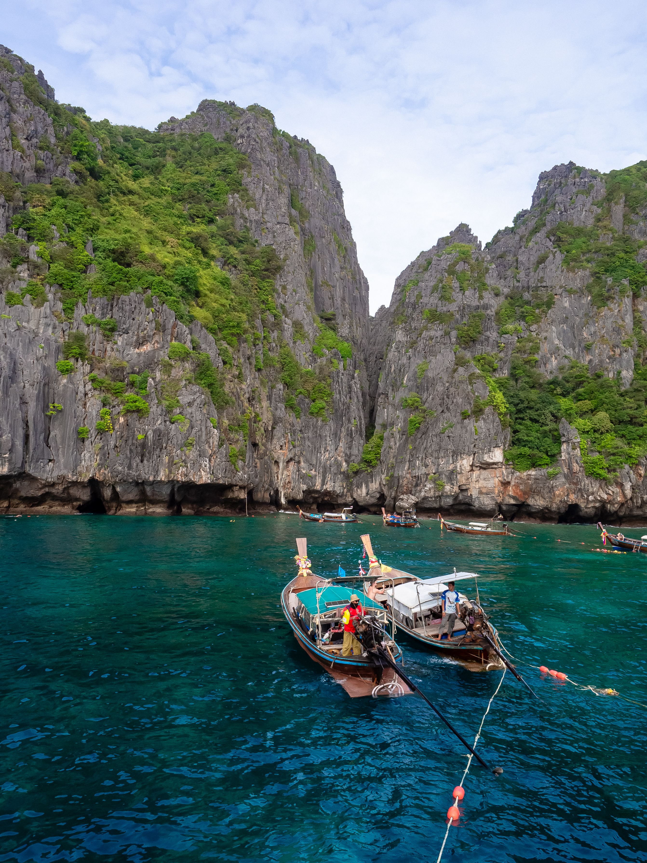 Longtail boats beneath limestone cliffs in Thailand