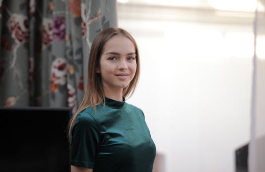 一位身穿绿色连衣裙的美丽女子在室内微笑，四周环绕着花卉窗帘