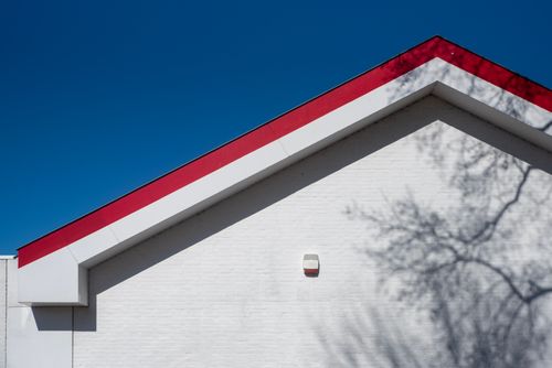 Free A minimalist building with a red and white geometric roof against a clear blue sky. Stock Photo