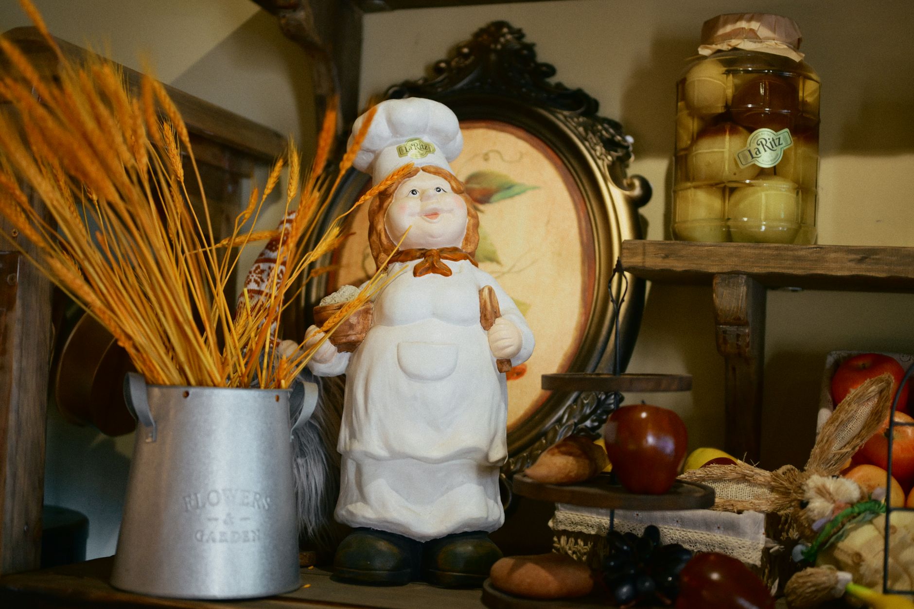 Charming rustic kitchen shelf featuring a chef figurine, vintage decor, and autumn harvest items.