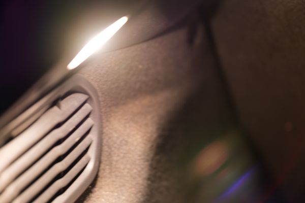 Gros plan macro sur une bouche d'aération de voiture, bokeh chaud et lumineux