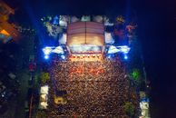 A breathtaking aerial shot capturing a lively concert crowd at night with bright stage lights.