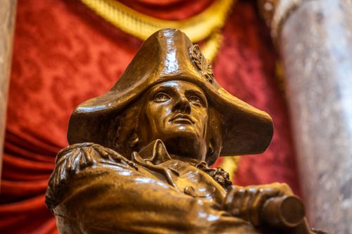 Free Impressive bronze statue of a naval officer in a detailed red velvet interior setting. Stock Photo