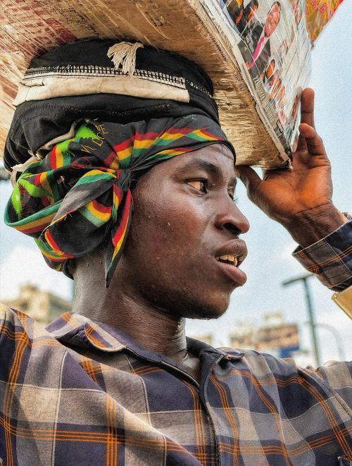 Free A man carries items balanced on his head, showing skill and tradition in an urban setting. Stock Photo