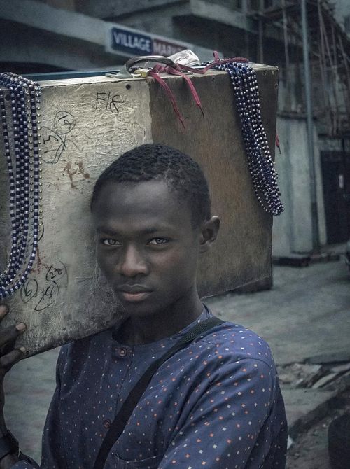 Free Portrait of a young Nigerian man carrying a box on a city street. Stock Photo