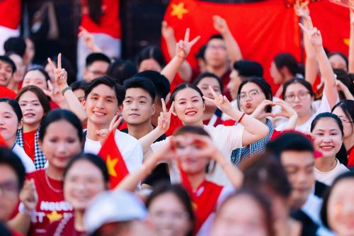 Free A lively group of people celebrating together with vibrant red flags in the background. Stock Photo