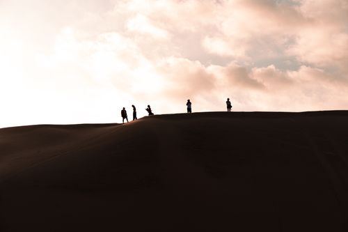 Free Silhouettes of people on sand dunes in Huacachina, Peru during a stunning sunset. Stock Photo