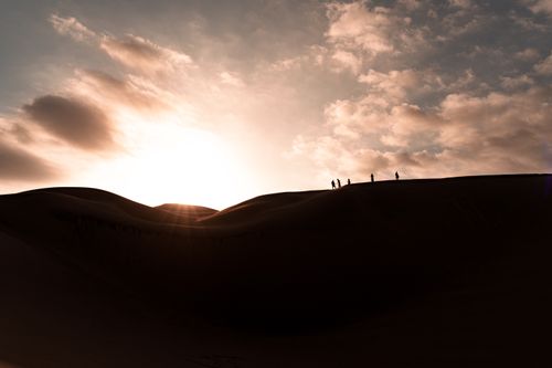 Free Silhouette of people walking on sand dunes during a dramatic sunset in Huacachina, Peru. Stock Photo