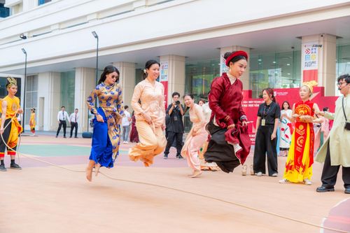 Free People in traditional outfits enjoying a vibrant Vietnamese rope jumping festival. Stock Photo