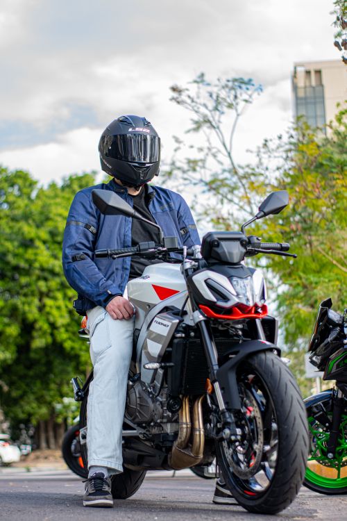 Free Man in helmet on a motorcycle, captured outdoors with a modern urban backdrop. Stock Photo