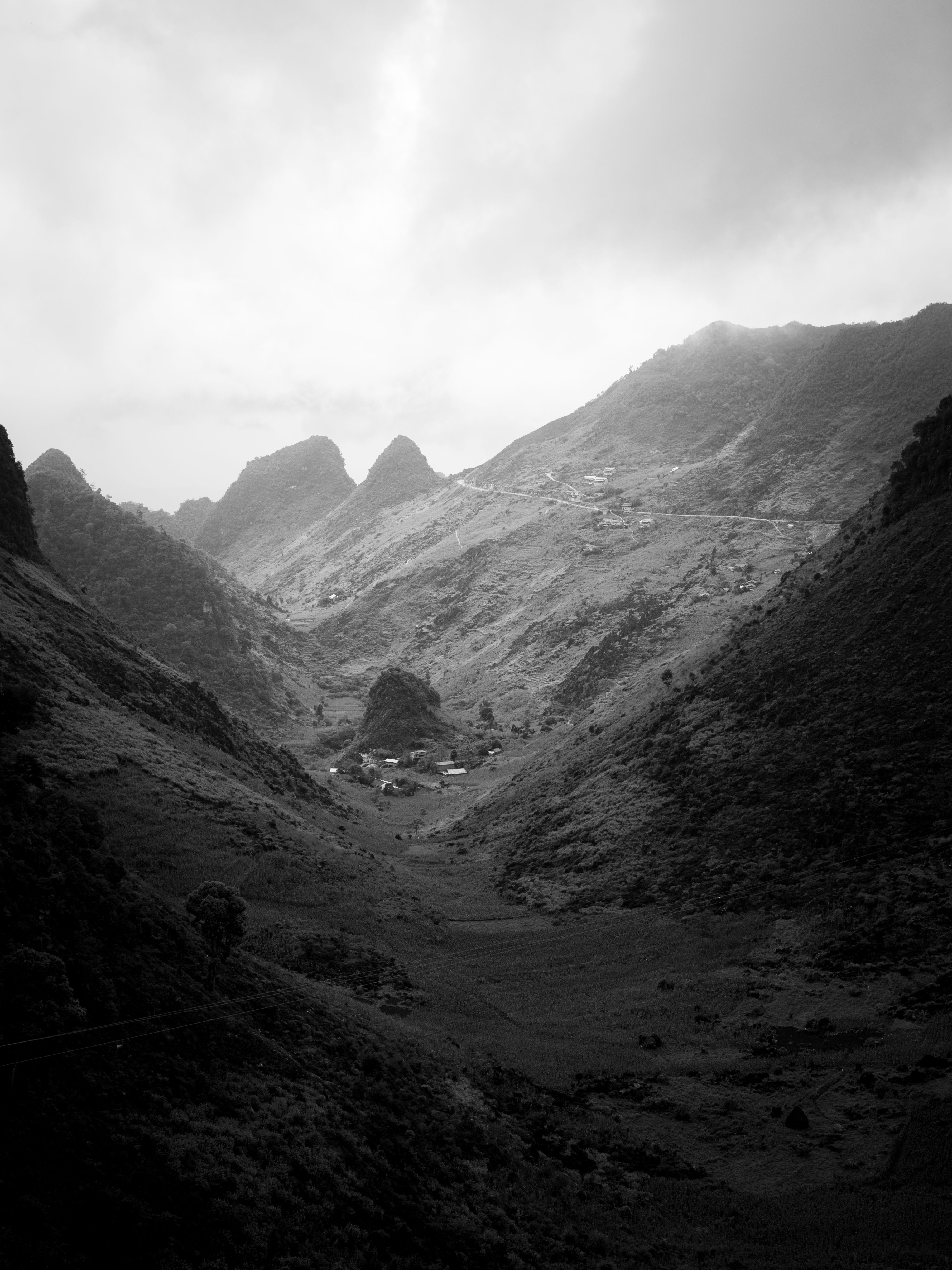 A dramatic black-and-white view of a misty mountain valley in Meo Vac, Vietnam.