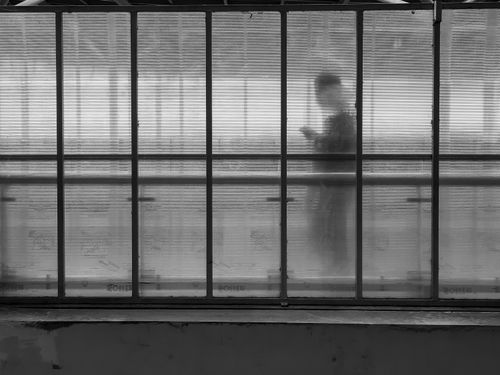 Free A mysterious silhouette of a person using a phone behind a translucent panel in Jakarta, Indonesia. Stock Photo