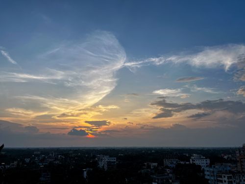 Free Beautiful sunset with clouds over city skyline, creating a serene atmosphere. Stock Photo
