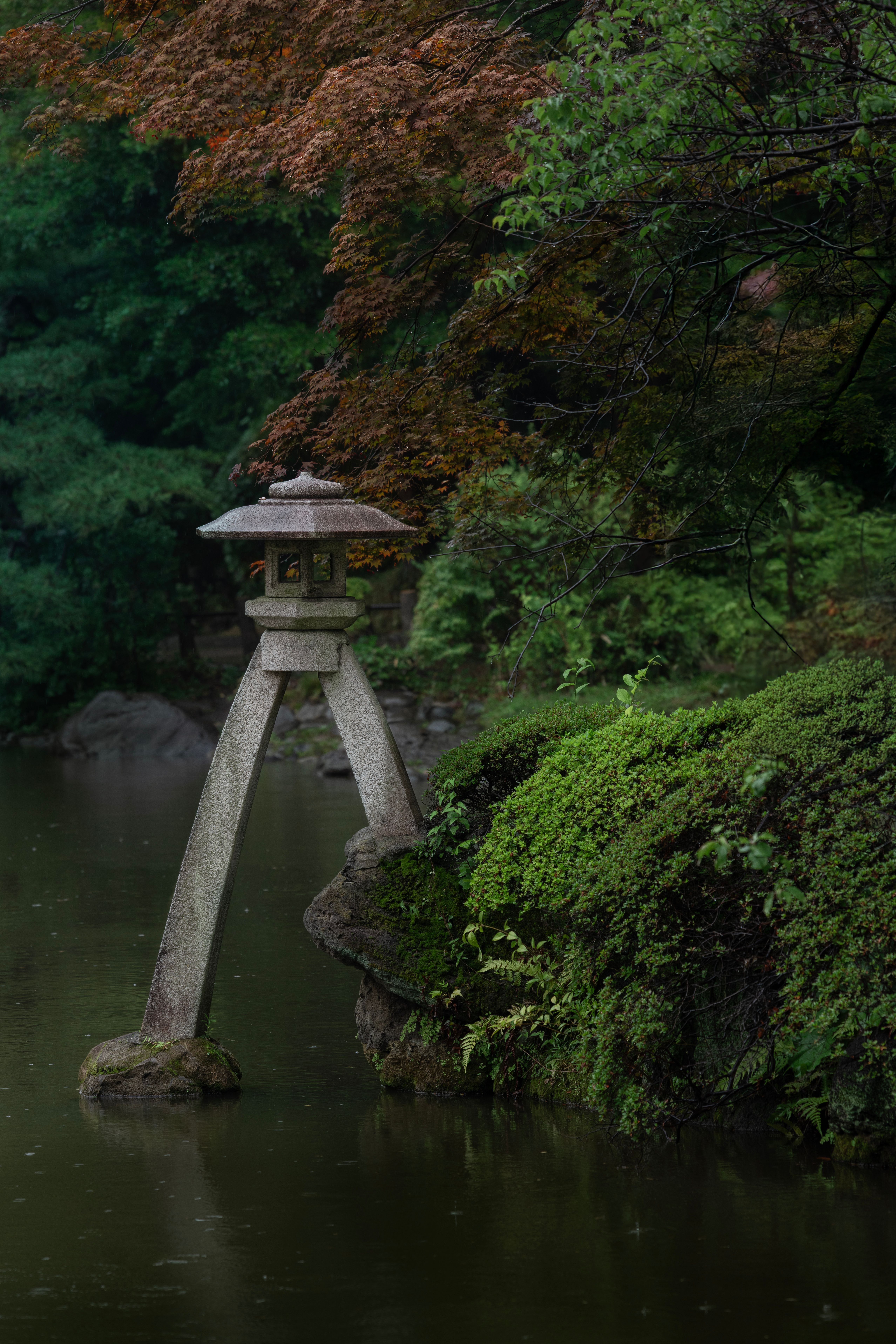 A tranquil Japanese garden scene with a traditional stone lantern by a pond in Tokyo.