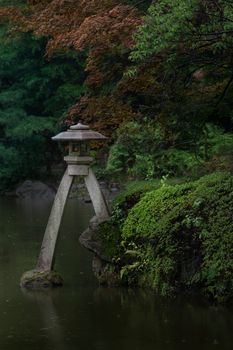A tranquil Japanese garden scene with a traditional stone lantern by a pond in Tokyo.