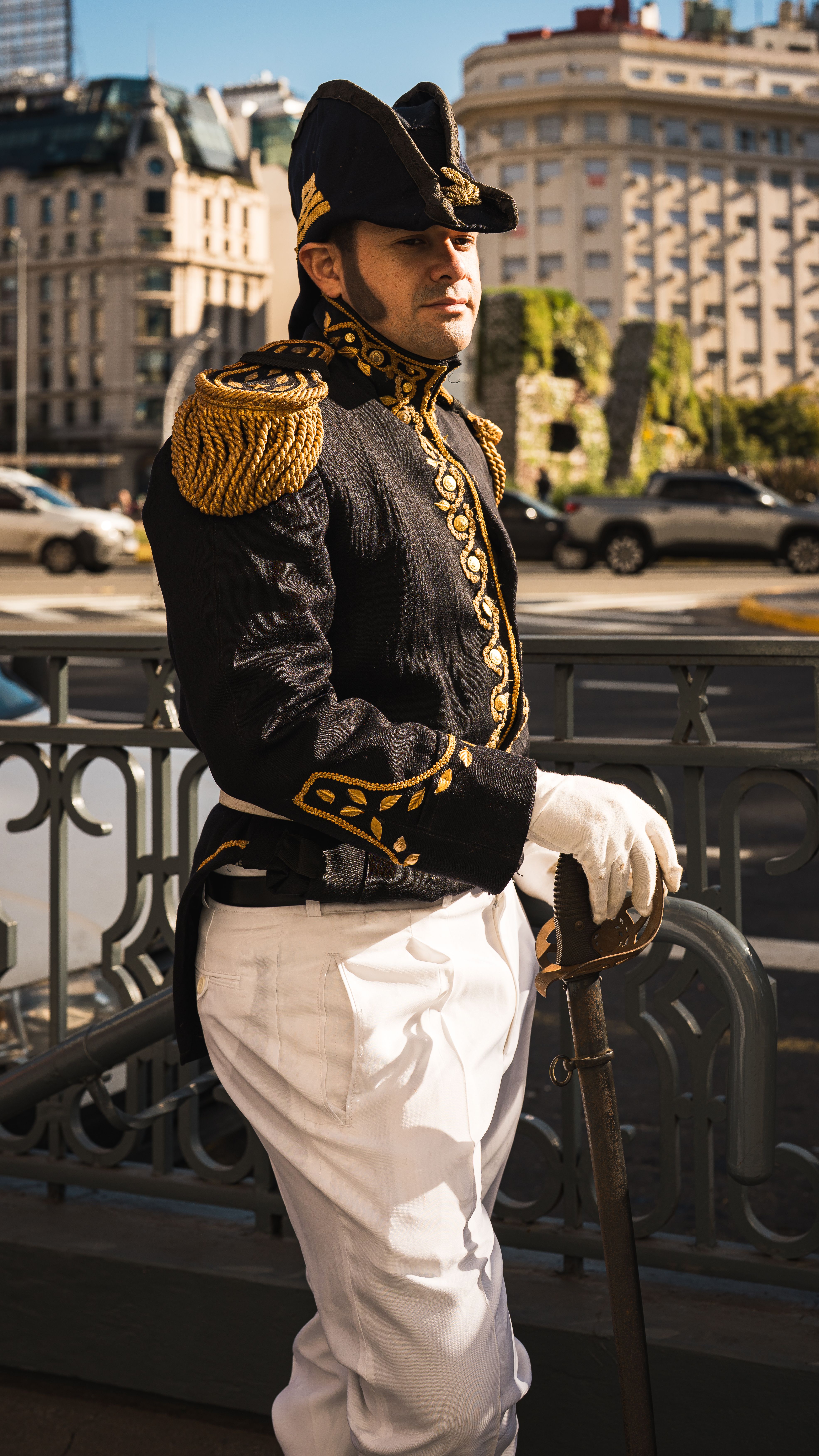 Male officer in ceremonial military uniform on city street.
