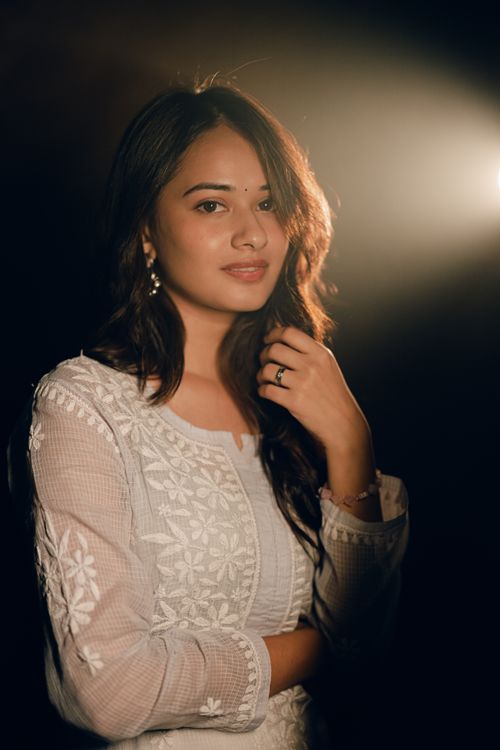Free Beautiful portrait of a woman wearing a white embroidered dress, illuminated by soft light. Stock Photo