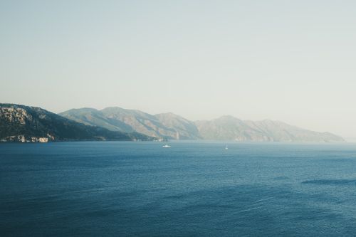 Free Calm blue sea with distant mountains under a clear sky near Mediterranean coast. Stock Photo