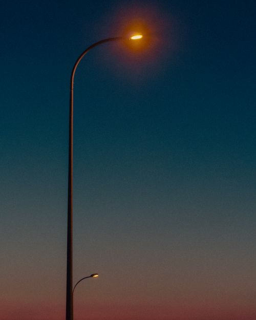 Free A single streetlight glowing warmly against a twilight sky, conveying solitude. Stock Photo