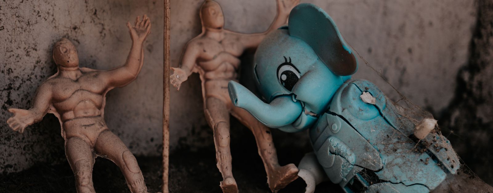 A collection of vintage toys and figurines, with Virgen de Guadalupe sign, in a dusty corner.
