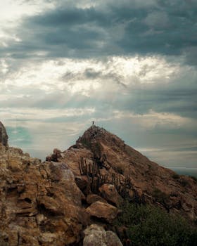 A rocky mountain with a visible cross at the peak under an overcast sky in Chiclayo, Peru.