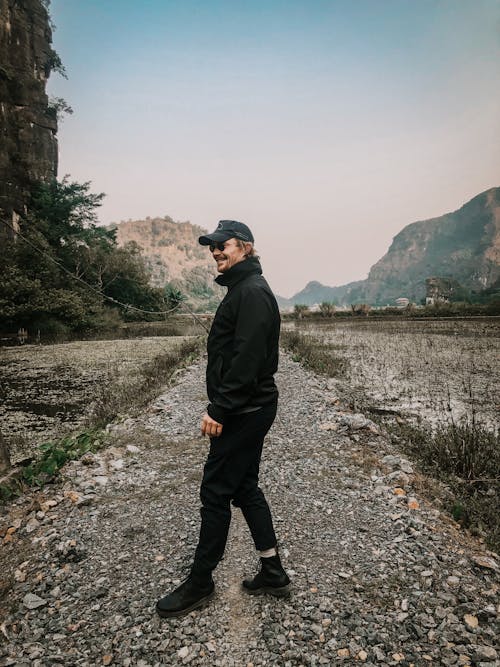 Free Man In Black Jacket Standing On Rocky Path Stock Photo
