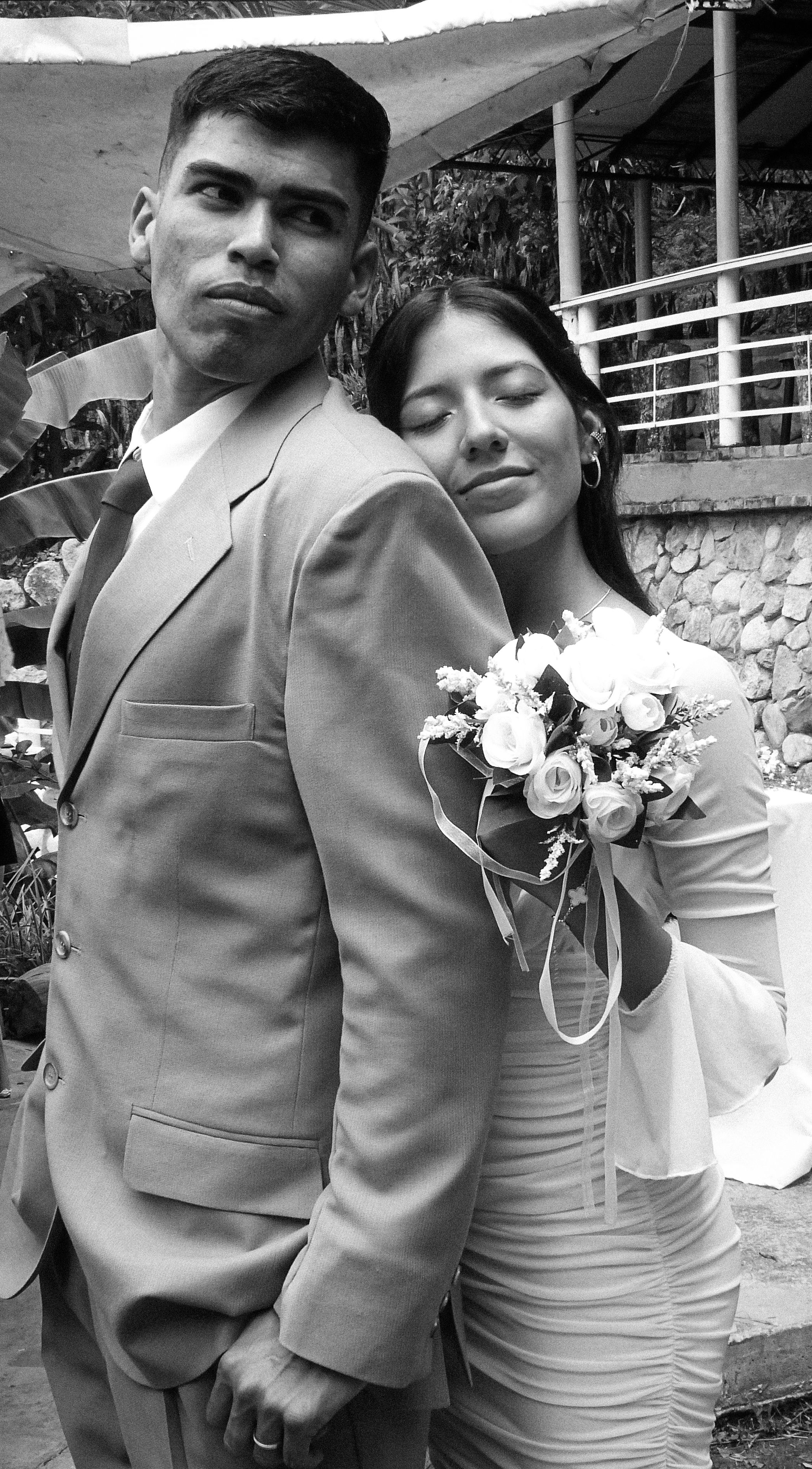 A romantic black and white portrait of a couple embracing outdoors during their wedding.