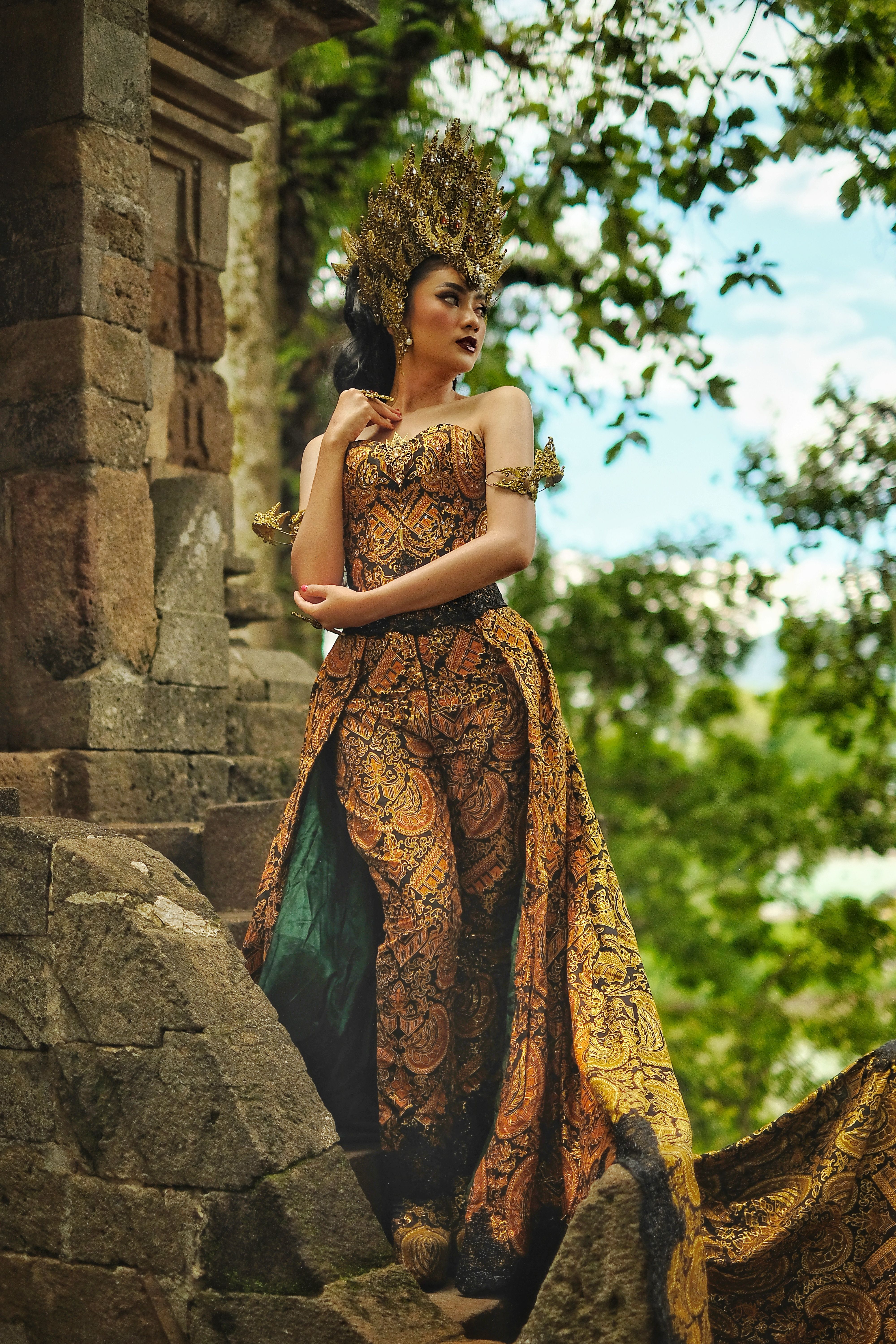 Woman in traditional Indonesian attire by ancient temple ruins in Garut, West Java.