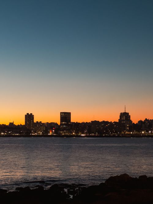 Free Captivating view of Montevideo's skyline at twilight over the river, showcasing vibrant city lights against a dusk sky. Stock Photo