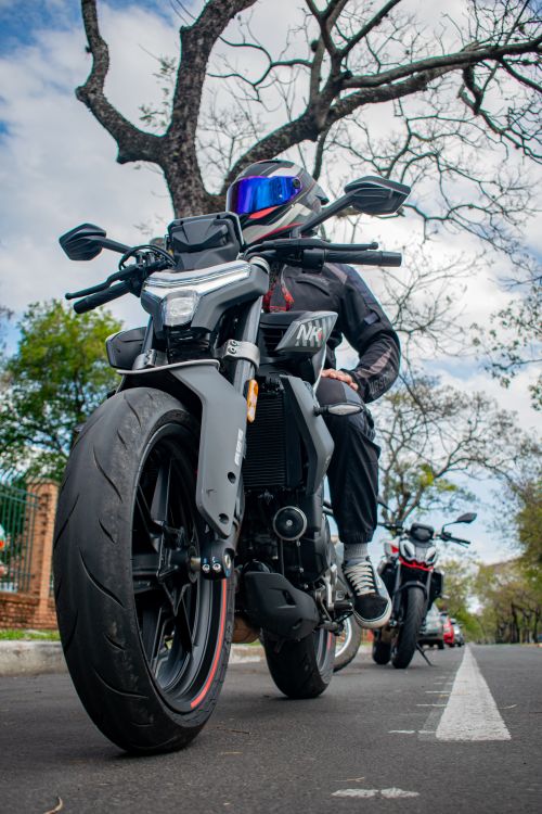 Free A motorcyclist wearing protective gear rides a sleek black motorcycle on a city street. Stock Photo