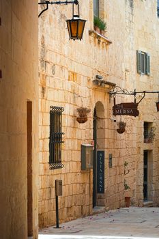 Historic stone buildings line a quaint street in Mdina, Malta, showcasing beautiful Mediterranean architecture.