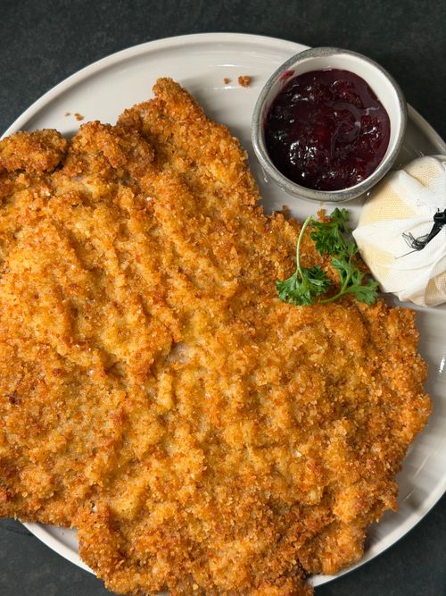 Free Delicious golden-brown schnitzel served with tangy cranberry sauce and fresh garnish. Stock Photo