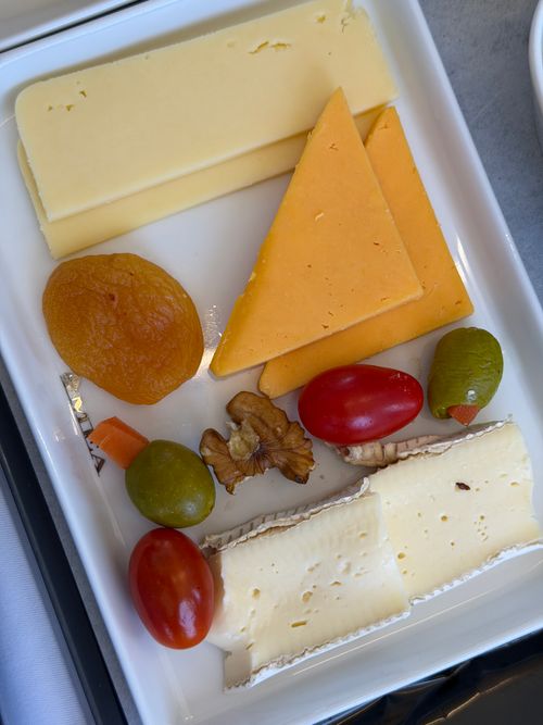 Free A selection of cheeses served with dried fruits, olives, and nuts on a white tray. Stock Photo