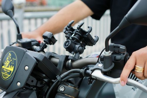 Free Close-up of a motorcycle handlebar with rider's hands. Outdoors scene. Stock Photo