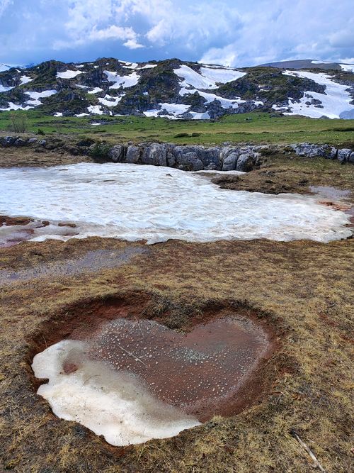 Free A heart-shaped patch of melting snow in a mountainous spring landscape. Stock Photo