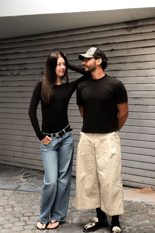 Free Stylish couple posing against a gray wall, showcasing casual urban fashion with a modern twist. Stock Photo