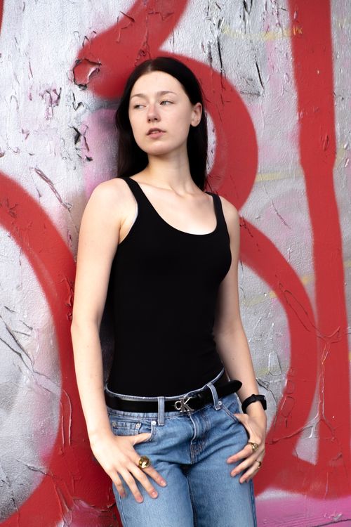 Free Woman in black top and jeans poses against a graffiti-covered wall. Stock Photo