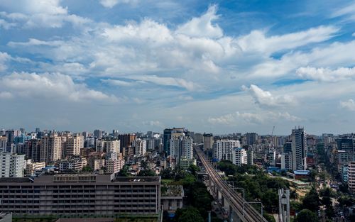 Free Vivid urban landscape of Dhaka, Bangladesh, featuring skyscrapers under a bright blue sky with fluffy clouds. Stock Photo