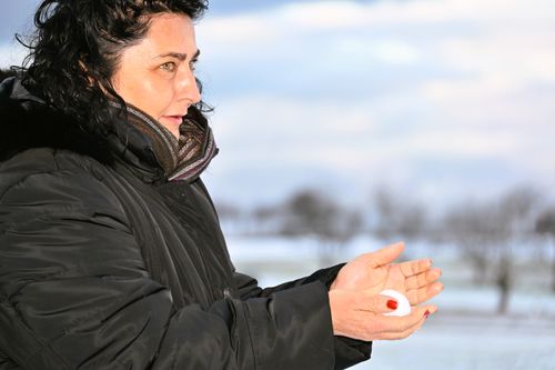 Free A woman in a winter coat holding a snowball in a snowy outdoor setting. Stock Photo