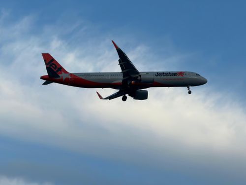 Free A commercial airplane flying against a clear blue sky with clouds. Stock Photo